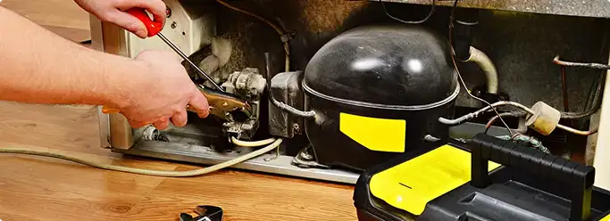 Refrigerator repair technician fixing the compressor and wiring in Ozark, MO