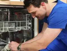 Dishwasher repair technician inspecting and servicing an open dishwasher in Springfield, MO