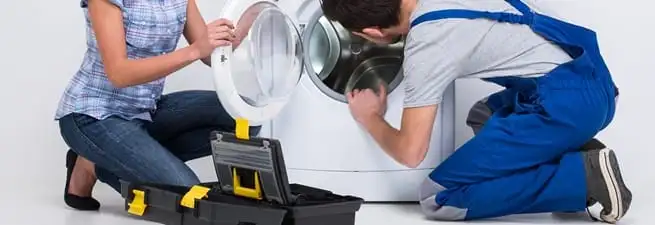 Washer repair technician inspecting a front-load washing machine with tools in Springfield, MO
