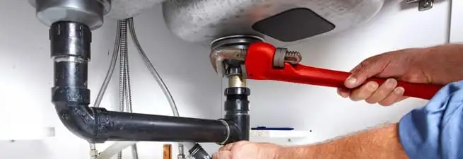 Garbage disposal repair technician tightening the sink drain and disposal connection in Springfield, MO
