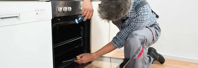 Oven repair technician inspecting and servicing an electric oven in Springfield, MO