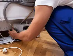 Appliance repair technician fixing refrigerator water line and connections in Springfield, MO