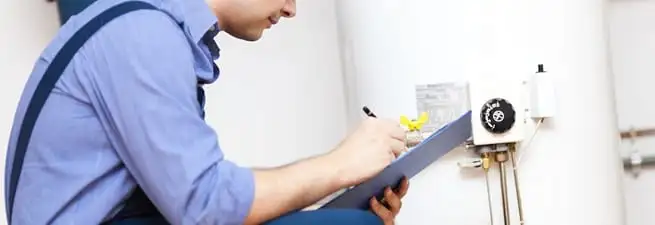 Water heater repair technician inspecting the unit and recording service notes in Springfield, MO
